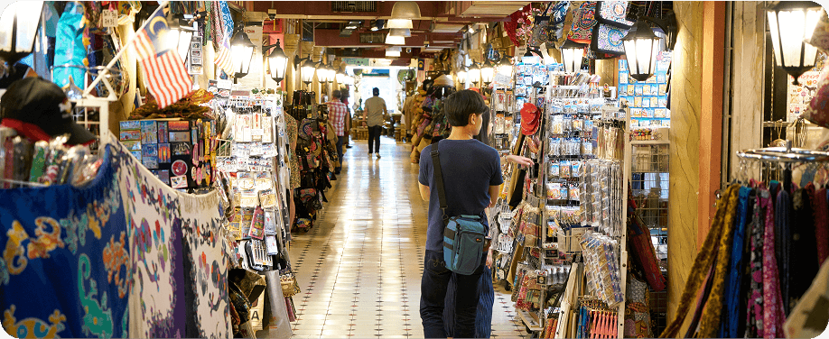 Busy market aisle with shoppers and goods.