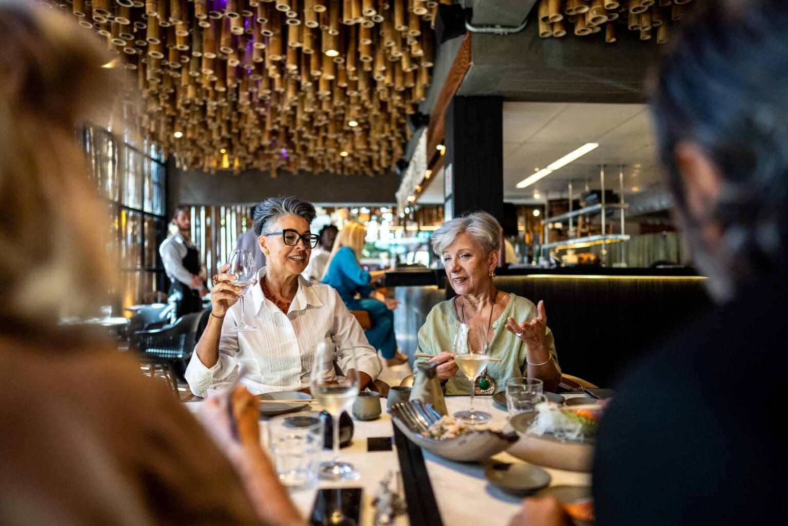 Two elderly women enjoying a meal together in a lively restaurant.