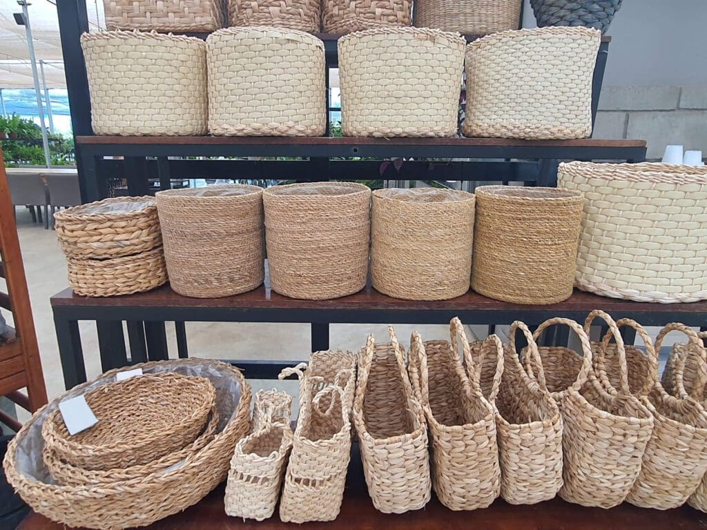 Handwoven baskets and bags displayed on shelves and floor.