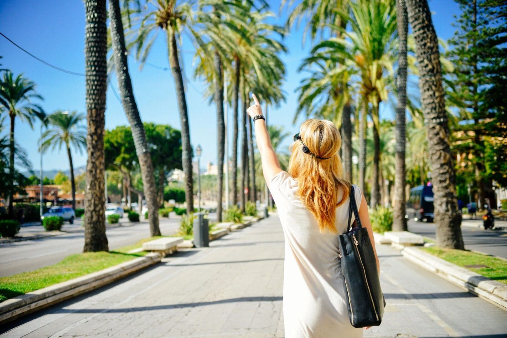 Woman walking along a palm tree avenue.