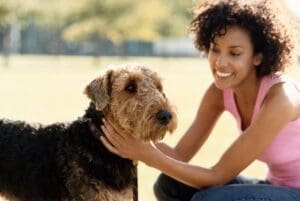 Woman smiling while petting a dog.