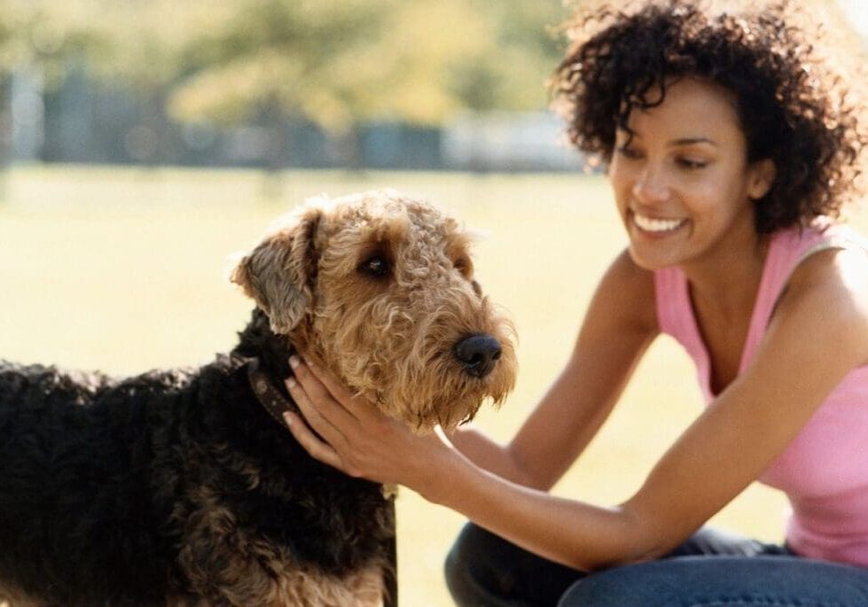 Woman smiling while petting a dog.